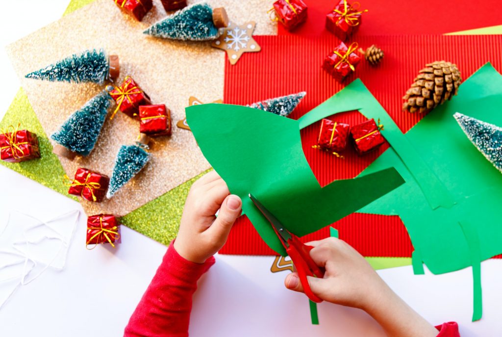 Kid playing with christmas crafts on white background.