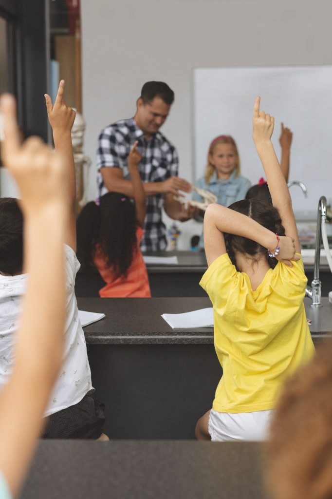 Schoolkids raising hand at school
